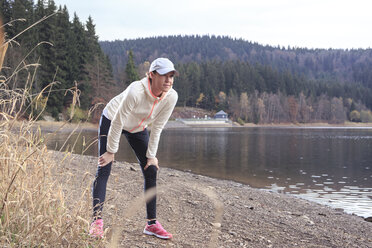 Female jogger having a rest at lakeshore - VTF000356