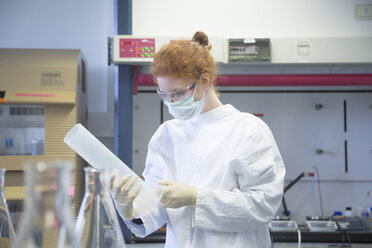 Young female natural scientist with mask working in biochemistry laboratory - SGF001149