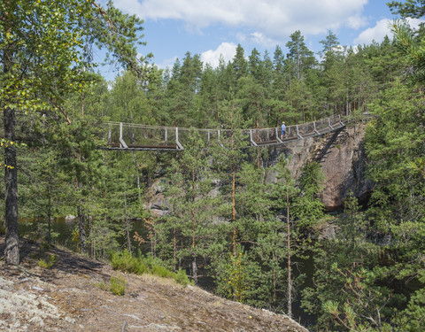 Finnland, Südsavoyen, Kymenlaakso, Repovesi-Nationalpark, Junge geht über die Lapinsalmi-Hängebrücke, lizenzfreies Stockfoto