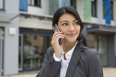 Portrait of smiling businesswoman telephoning with smartphone - SHKF000039