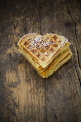 Stapel herzförmiger Waffeln mit Puderzucker bestreut auf dunklem Holz - LVF002368