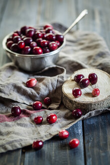 Metallschale mit Preiselbeeren, Vaccinium macrocarpon, auf Küchentuch und Holz - SBDF001505