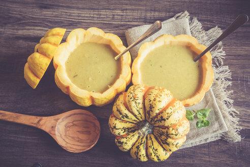 Kürbiscremesuppe in ausgehöhlten Chamäleonkürbissen auf Stoff und dunklem Holz - SARF001090