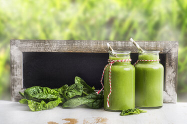 Two glasses of spinach smoothie, spinach leaves and blackboard - ODF000899