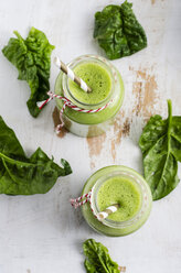 Two glasses of spinach smoothie and spinach leaves on white wood - ODF000905