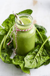 Glass of spinach smoothie and spinach leaves on white wood - ODF000906