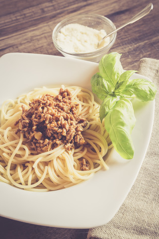 Spaghetti mit Bolognesesauce, Basilikum und Parmesan auf dem Teller, lizenzfreies Stockfoto