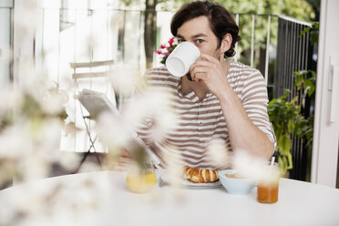 Man with coffee and newspaper having breakfast - FMKF001366