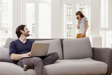 Couple using laptop and cell phone at home - FMKF001389