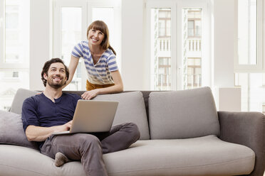 Smiling couple with laptop at home - FMKF001390