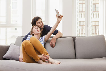 Happy couple taking selfie at home - FMKF001434