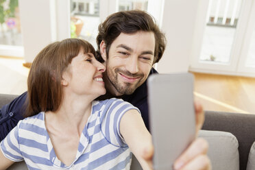 Glückliches Paar nimmt Selfie zu Hause - FMKF001391