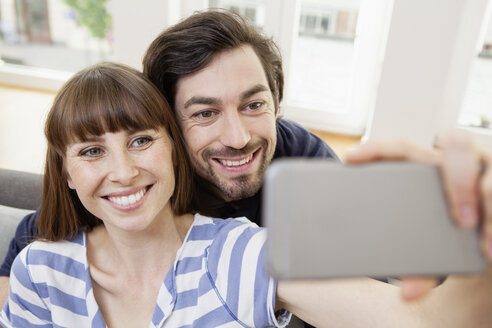 Glückliches Paar nimmt Selfie zu Hause - FMKF001392