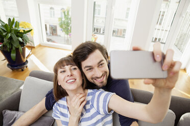 Happy couple taking selfie at home - FMKF001393