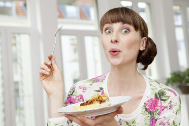 Smiling woman enjoying piece of cake - FMKF001406