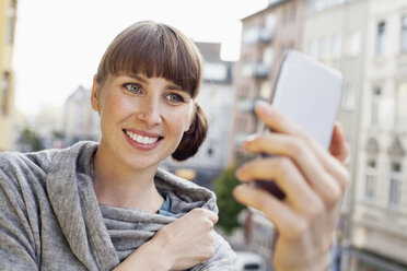 Smiling woman taking selfie on balcony - FMKF001411