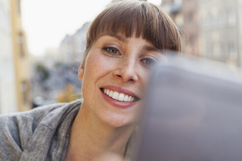 Lächelnde Frau nimmt Selfie auf Balkon - FMKF001436