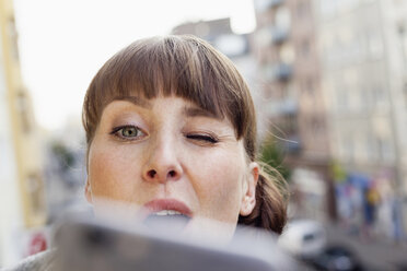 Frau zwinkert und macht Selfie auf Balkon - FMKF001412