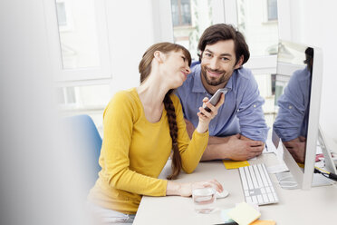 Ehepaar mit Handy am Schreibtisch im Home Office - FMKF001441