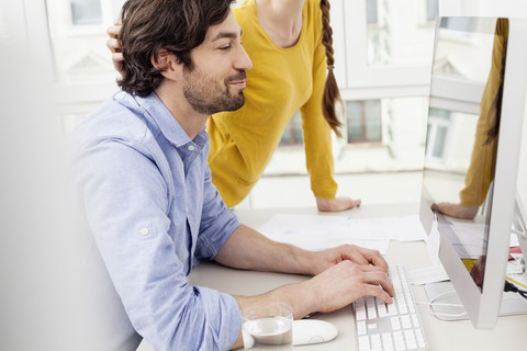 Ehepaar im Heimbüro mit Mann am Computer, lizenzfreies Stockfoto