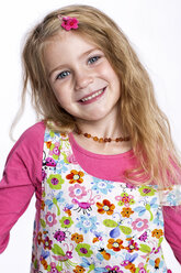 Porträt eines lächelnden blonden Mädchens im bunten Kleid vor weißem Hintergrund - GDF000621