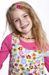 Portrait of smiling blond girl wearing colourful dress in front of white background - GDF000621