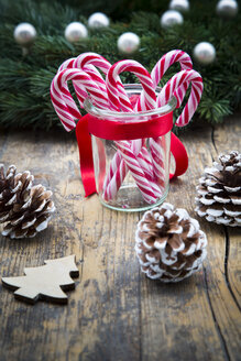 Glas mit Zuckerstangen und Tannenzapfen auf Holz - LVF002393