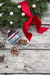 Adventskranz mit roter Schleife, Weihnachtskugel und Tannenzapfen auf Holz - LVF002398