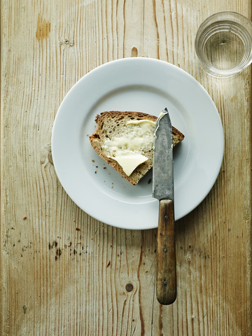 Ein Glas Wasser und ein Teller mit Brot und Butter, lizenzfreies Stockfoto