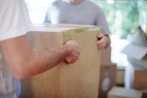 Zwei Männer ziehen um und tragen eine Kiste, lizenzfreies Stockfoto