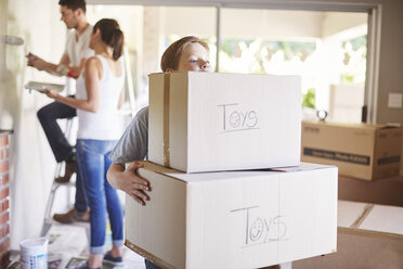 Family moving house, boy carrying boxes - ZEF002882