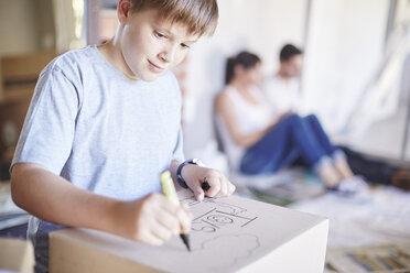 Family moving house, boy writing on a box - ZEF002883