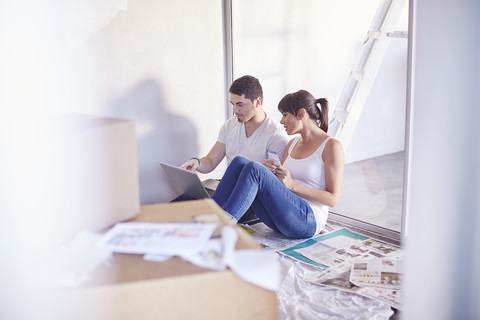 Ehepaar mit Laptop gönnt sich eine Pause von der Renovierung des neuen Hauses, lizenzfreies Stockfoto