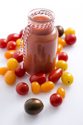 Glass of tomato smoothie and different tomatoes on white ground - ODF000907