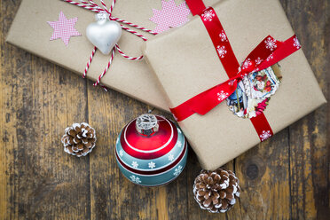 Wrapped Christmas presents, Christmas bauble and fir cones on dark wood - LVF002408