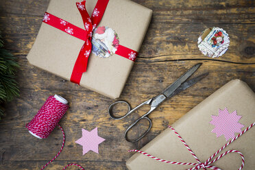 Eingepackte Weihnachtsgeschenke und Schere auf dunklem Holz - LVF002407