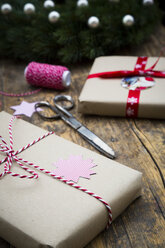 Eingepackte Weihnachtsgeschenke und Schere auf dunklem Holz - LVF002406