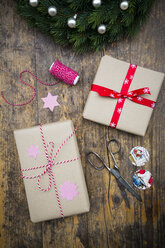 Eingepackte Weihnachtsgeschenke und Schere auf dunklem Holz - LVF002405
