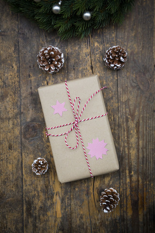 Eingepacktes Weihnachtsgeschenk und Tannenzapfen auf dunklem Holz, lizenzfreies Stockfoto