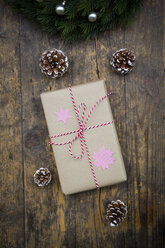 Eingepacktes Weihnachtsgeschenk und Tannenzapfen auf dunklem Holz - LVF002404