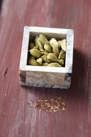 Kleine Schachtel mit Kardamomkapseln auf Holz, lizenzfreies Stockfoto