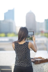 Junge Frau fotografiert mit digitalem Tablet in der Stadt - ZEF001551