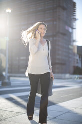 Frau mit Mobiltelefon beim Spaziergang in der Stadt - ZEF001567