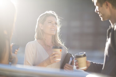 Three people with coffee to go talking outdoors - ZEF001572