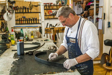 Saddler dyeing edges of leather strap with leather paint - TCF004385