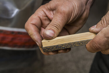 Messermacher hält ein Stück Holz in der Werkstatt - TCF004414