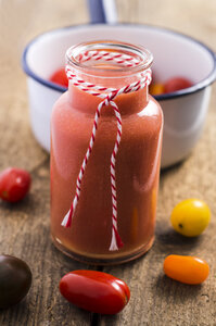 Glas mit Tomatensmoothie und verschiedenen Mini-Tomaten auf Holz - ODF000909