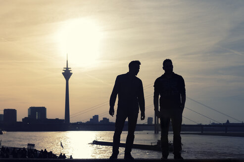 Germany, North Rhine-Westphalia, Duesseldorf, two man looking to Rhine tower and Rhine river at sunset - FRF000140