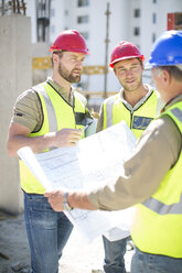 Bauarbeiter besprechen Baupläne auf einer Baustelle - ZEF001588