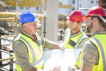 Bauarbeiter besprechen Baupläne auf einer Baustelle - ZEF001592